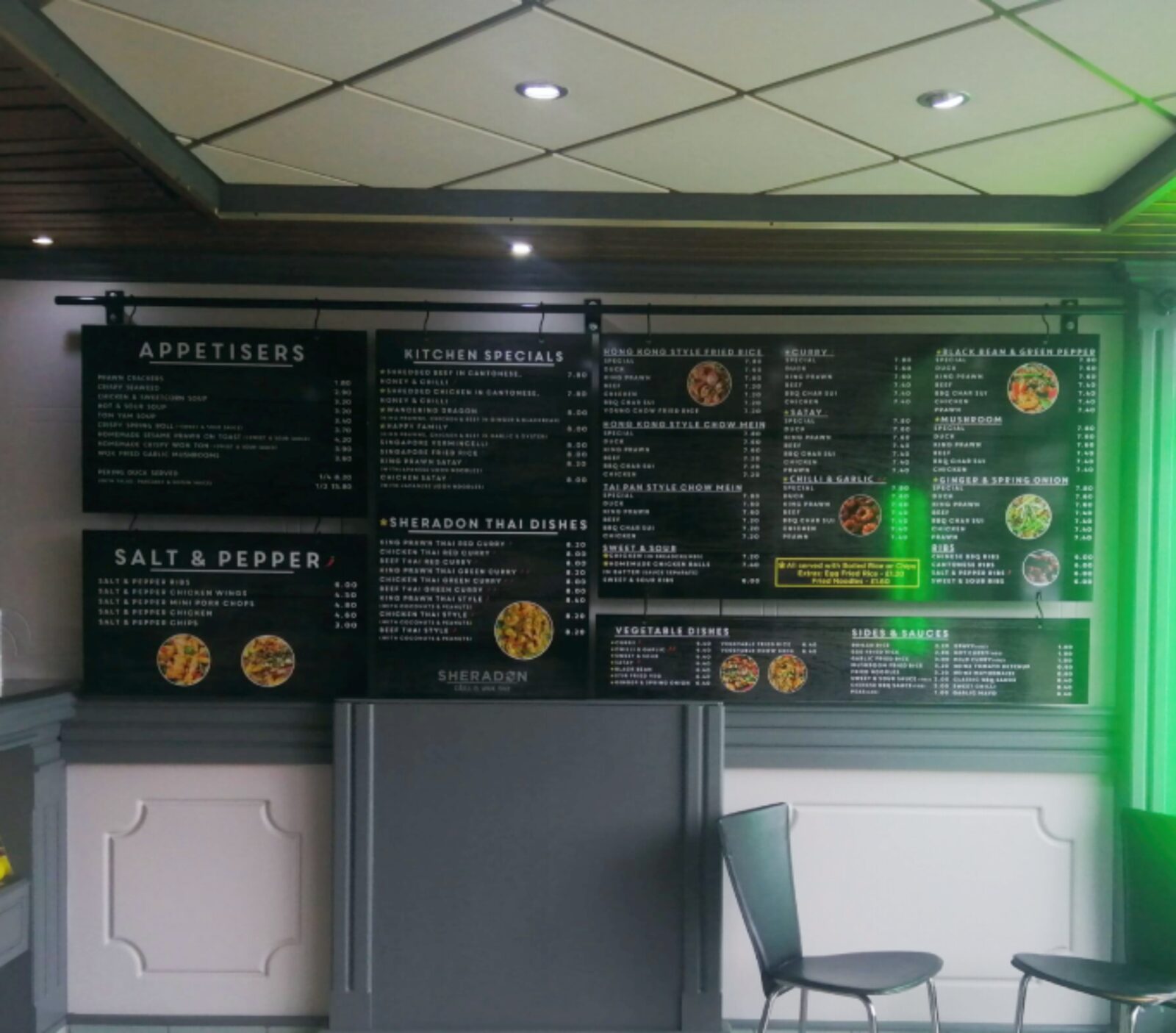 Full wall of hanging menu boards above a takeaway counter