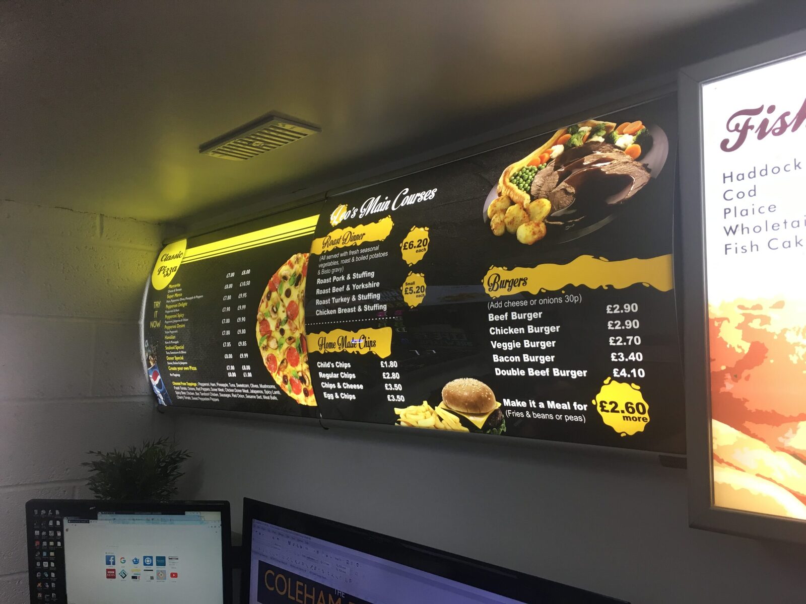 Curved black and yellow illuminated menu boards for a pizza and roast dinner menu