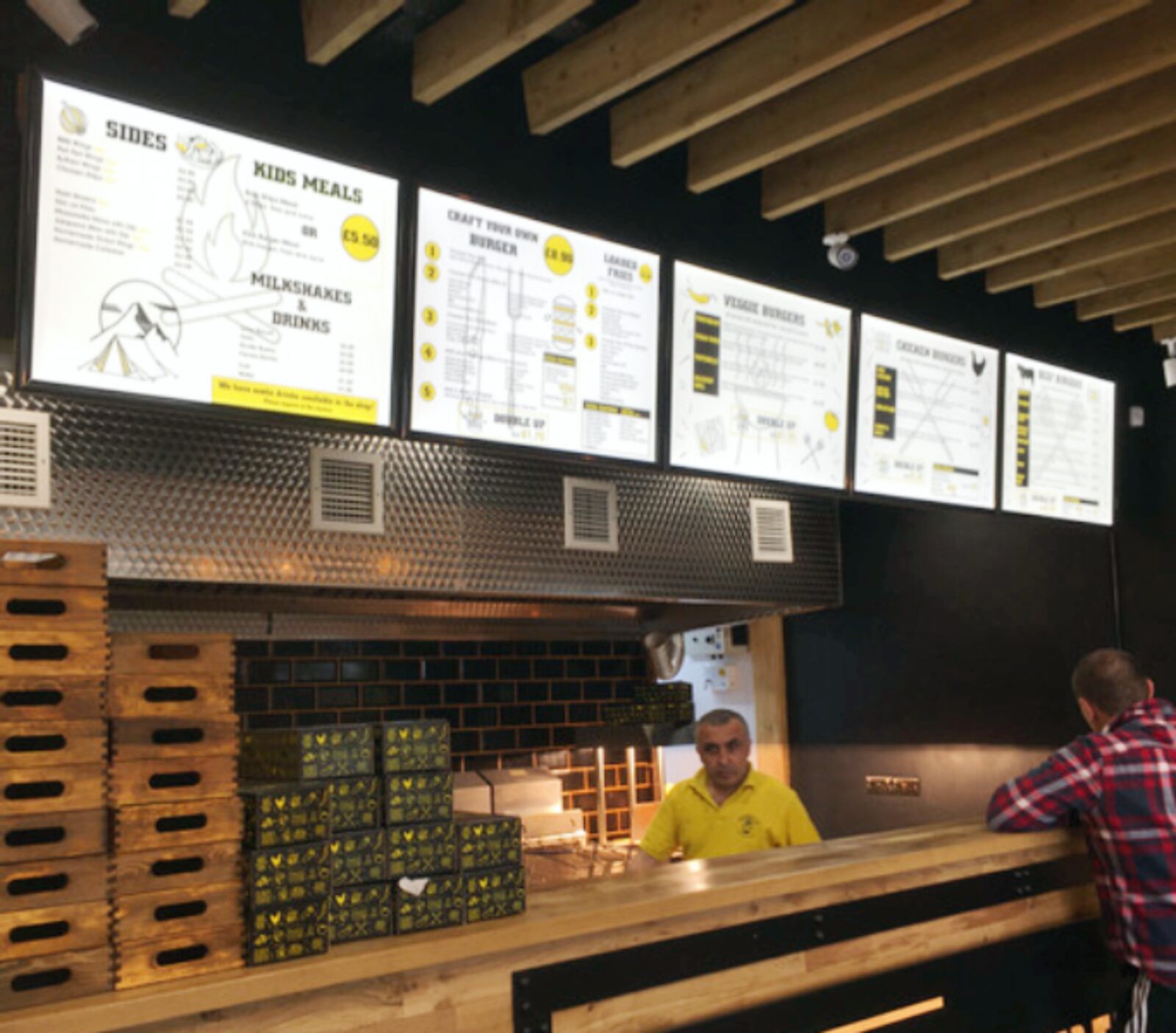 Yellow and white illuminated menu panels above a burger counter