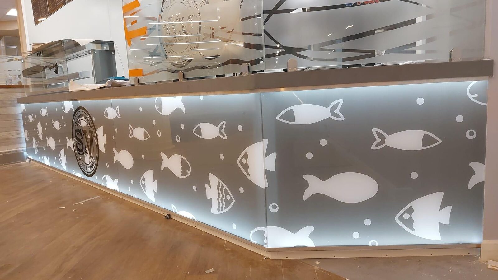 Etched fish window graphics along a branded counter